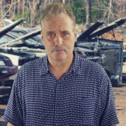 Man with light brown hair and a salt-and-pepper mustache, a row of cars with hoods open